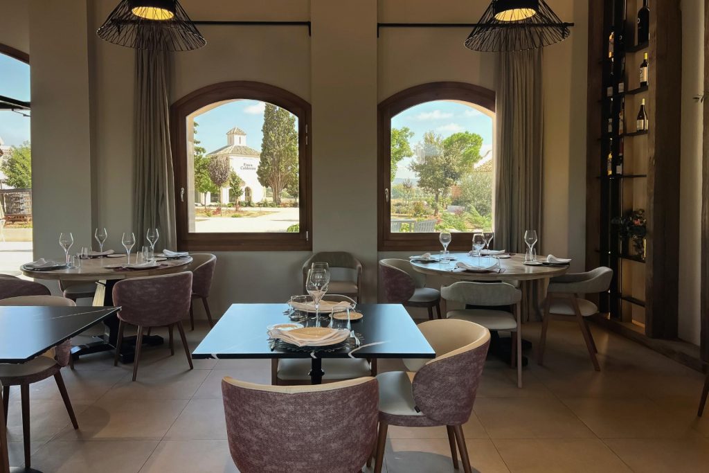 Mesas del restaurante gourmet de la bodega Finca Calderón con vistas al viñedo y al hotel enoresort en Requena