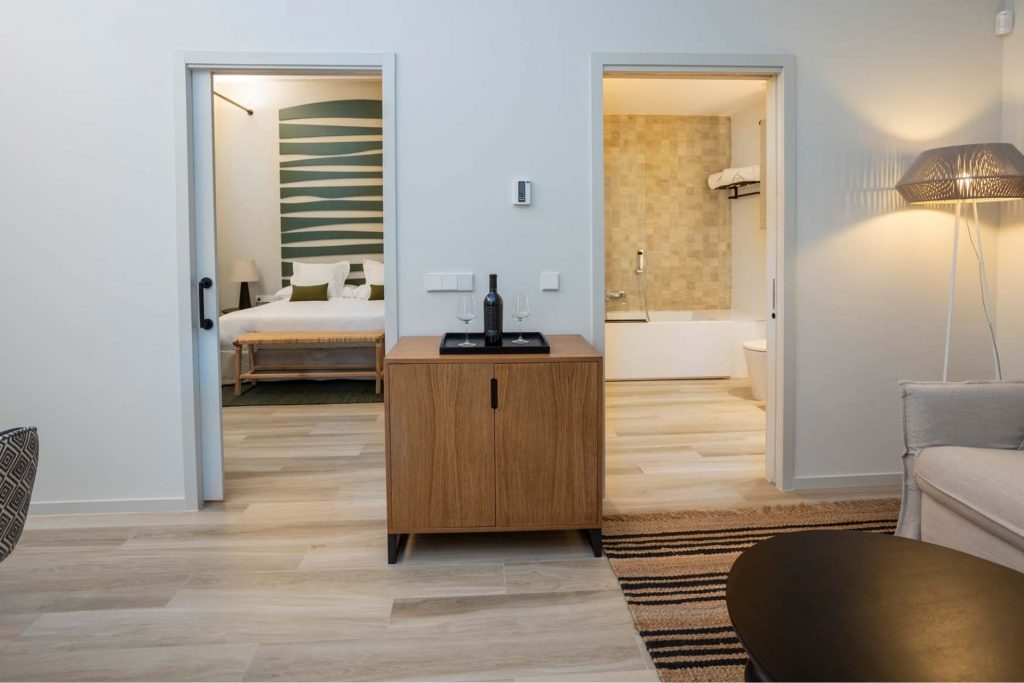Spacious premium suite at Hotel Finca Calderón, featuring a private lounge, queen-size bed, and hydromassage bathtub with views overlooking the vineyards.